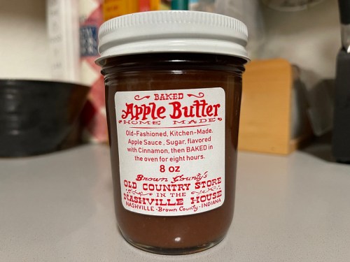 A jar of homemade baked apple butter with a vintage label, featuring ingredients and a nostalgic design.