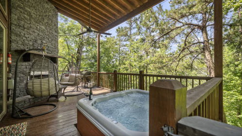 A serene outdoor deck with a hot tub, surrounded by lush greenery and comfortable seating.