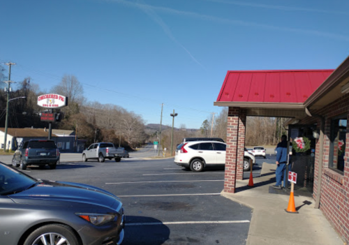 A parking lot with several cars outside a restaurant featuring a red roof and a sign in the background.