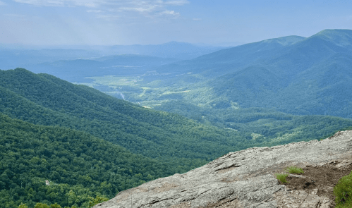 A panoramic view of lush green mountains and valleys under a clear blue sky.