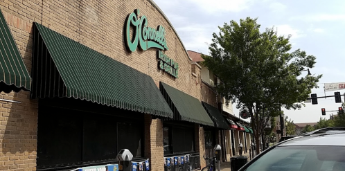 Exterior of O'Connell's Irish Pub & Grill, featuring green awnings and a brick facade, with nearby street signs and trees.