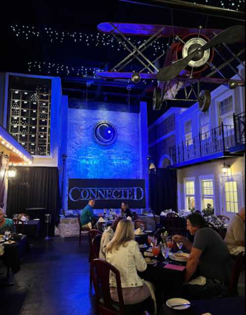 A stylish restaurant interior with blue lighting, a vintage airplane decor, and diners enjoying their meals.