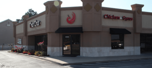 Exterior of a restaurant featuring a sign for "Chicken Gyros" with a modern design and landscaping in front.