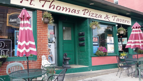 Exterior of Ft. Thomas Pizza & Tavern, featuring a green door, outdoor seating, and decorative plants.