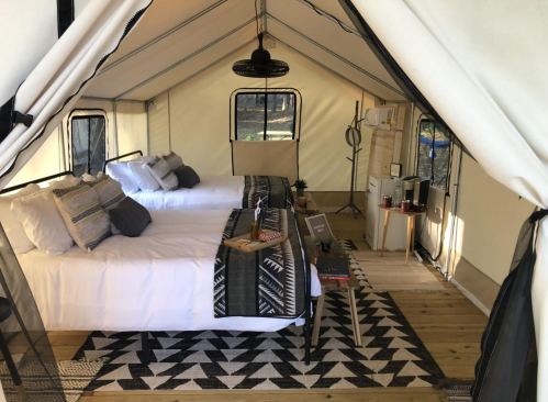 Interior of a glamping tent featuring two beds, a rug, and various furnishings for a cozy atmosphere.