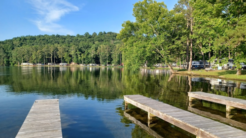 A serene lake scene with wooden docks, surrounded by lush green trees and a calm water reflection.