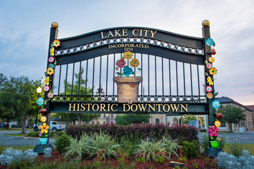 Sign for Lake City, established in 1859, featuring colorful flowers and the words "Historic Downtown."