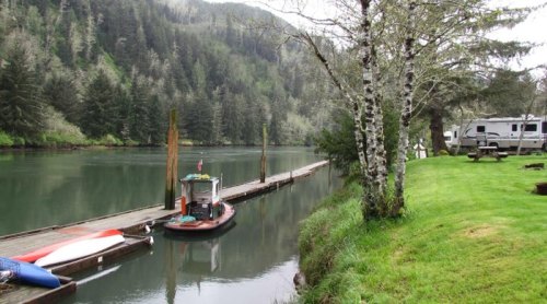 A serene river scene with a dock, a small boat, and lush greenery along the water's edge.