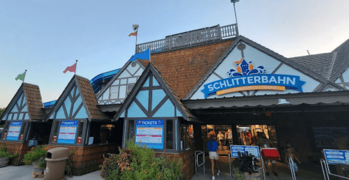 Entrance to Schlitterbahn water park featuring a wooden facade and ticket booths. Flags wave above the building.