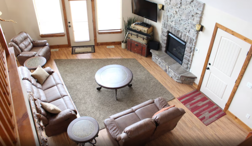 Cozy living room with leather sofas, a stone fireplace, and a round coffee table on a large area rug.