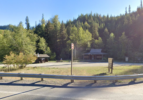 A scenic view of a roadside area with trees, a parking lot, and a small building in a forested setting.