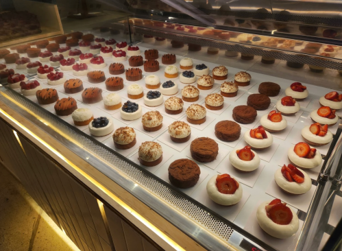 A display case filled with various decorative desserts, including cakes topped with fruits and cream.