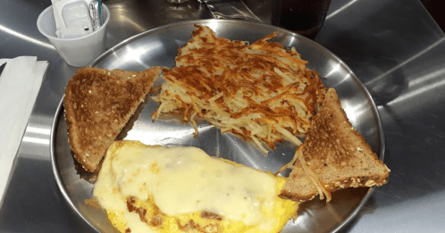 A plate with a cheese omelet, hash browns, and toasted bread slices, served on a stainless steel tray.