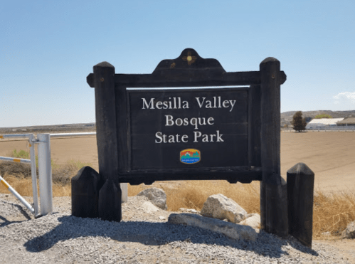 Sign for Mesilla Valley Bosque State Park, with a clear blue sky and open landscape in the background.
