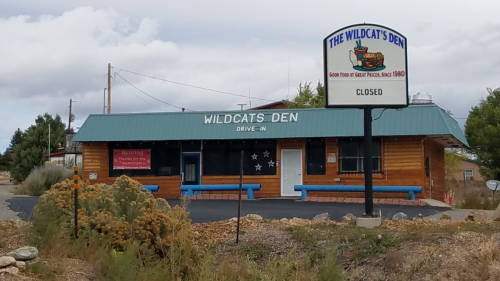 A closed drive-in restaurant named "The Wildcat's Den," featuring a wooden exterior and a sign indicating it's been in business since 1980.