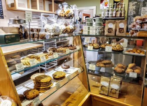 A display case filled with various cookies and baked goods in a cozy bakery setting.