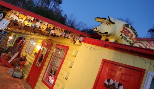 A colorful building with a large pig statue on the roof, decorated with festive lights and holiday ornaments.