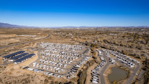 Aerial view of a large RV park with numerous parked RVs, surrounded by desert landscape and mountains in the distance.