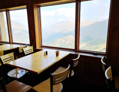 A cozy dining area with wooden walls and large windows showcasing a scenic mountain view.