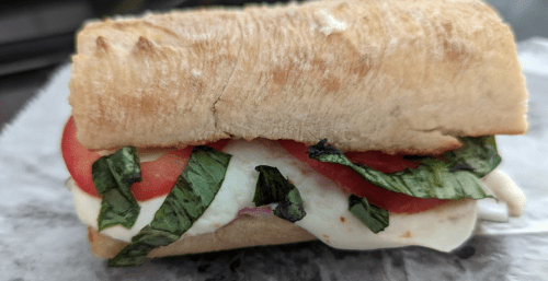 A sandwich with fresh mozzarella, tomatoes, and basil on a toasted ciabatta roll.