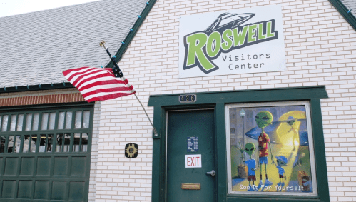 Exterior of the Roswell Visitors Center featuring an alien-themed window display and an American flag.