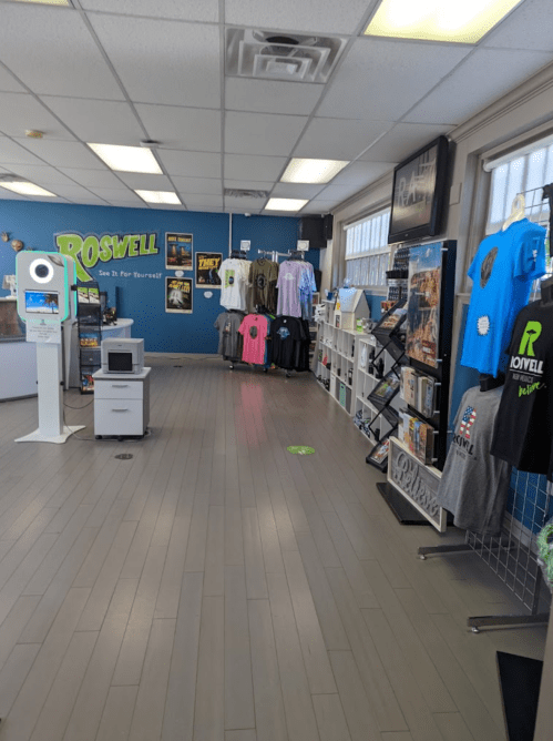 Interior of a store featuring merchandise displays, clothing racks, and a photo booth in a bright, organized space.