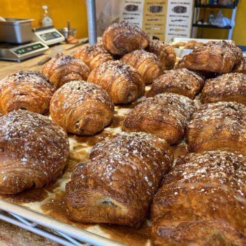 A tray of freshly baked, golden-brown croissants topped with a sprinkle of sugar.
