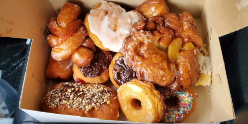 A box filled with assorted donuts, including glazed, chocolate-covered, and sprinkled varieties.