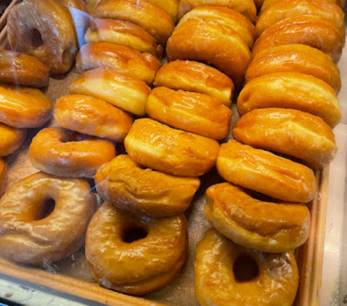 A display of glazed donuts arranged in a tray, showcasing their golden-brown color and shiny glaze.