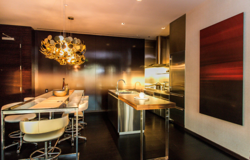 Modern kitchen with sleek stainless steel appliances, a stylish chandelier, and a minimalist dining area.
