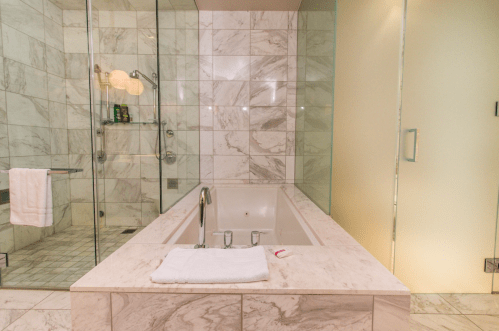 Modern bathroom featuring a marble tub, glass shower, and elegant tile work. Soft lighting enhances the serene atmosphere.
