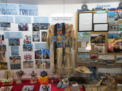 Display featuring Native American artifacts, traditional clothing, and informational panels about cultural events and history.
