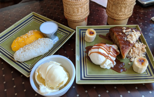 A plate with mango sticky rice, coconut sauce, banana cake, ice cream, and caramel drizzle, served in decorative dishes.
