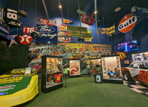 A vibrant museum exhibit featuring racing memorabilia, cars, and colorful banners on the walls.