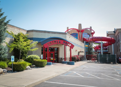 Exterior view of a building with "Triple Play" signage, featuring a colorful water slide in the background.