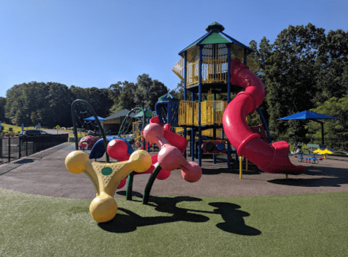 Colorful playground with a tall structure, slides, and climbing equipment under a clear blue sky.
