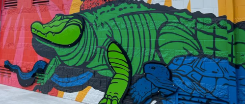 Colorful mural featuring a large green crocodile against a vibrant background of red, blue, and yellow.