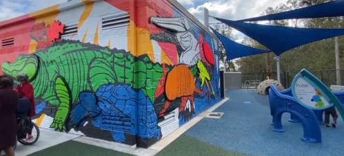 Colorful mural of animals on a playground wall, featuring a crocodile, turtle, and other vibrant designs.