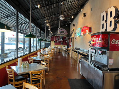 Interior of a casual restaurant with tables, neon signs, and a soda fountain, featuring a bright and inviting atmosphere.