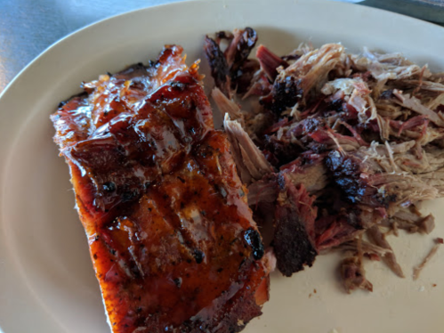 A plate featuring a piece of glazed barbecue meat alongside shredded, smoky pulled pork.