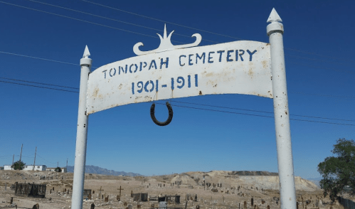 Sign for Tonopah Cemetery, dated 1901-1911, with a clear blue sky and cemetery grounds visible in the background.