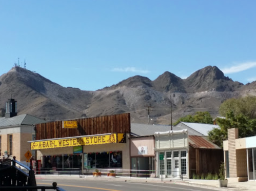 A western store with a wooden facade in front of mountains under a clear blue sky.