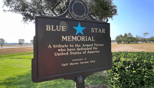 A sign reading "Blue Star Memorial" honoring the U.S. Armed Forces, sponsored by the Gulf Shores Garden Club.