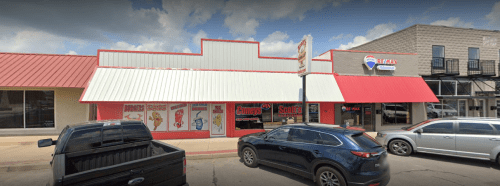 A storefront with a red and white roof, featuring signage for a restaurant and nearby parking.