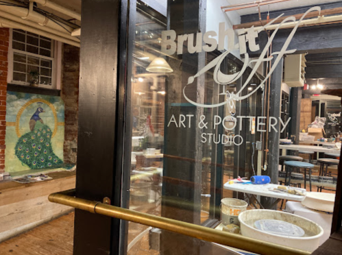 Entrance to Brush It Art & Pottery Studio, featuring a peacock mural and pottery supplies inside.