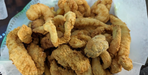 A pile of crispy, golden-brown fried seafood, served on a white paper liner.