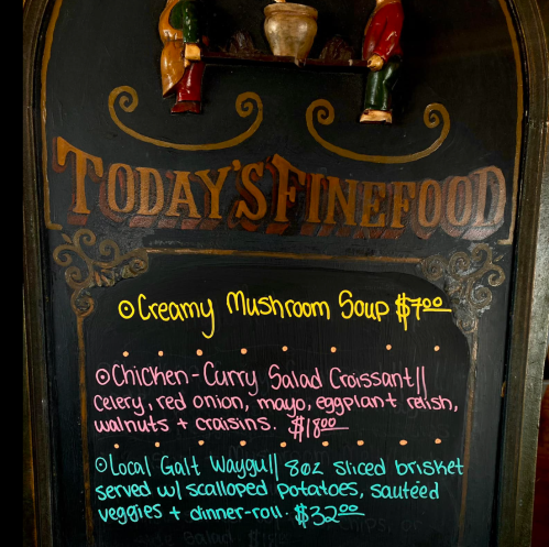 Chalkboard menu listing: creamy mushroom soup, chicken curry salad croissant, and local Galt Waygu beef with sides.