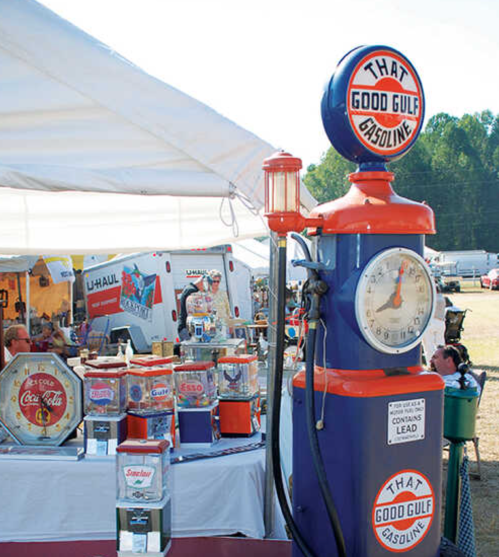 Vintage gas pump with "That Good Gulf Gasoline" sign, surrounded by retro collectibles at an outdoor market.