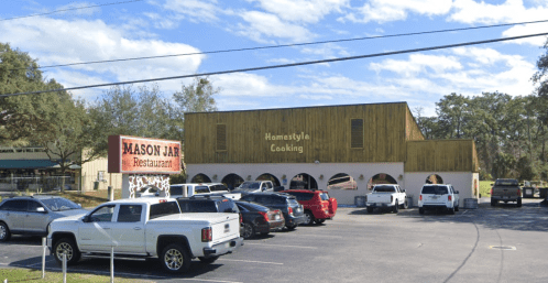 A restaurant building with a sign reading "Homestyle Cooking" and "Mason Jar" in front, surrounded by parked cars.