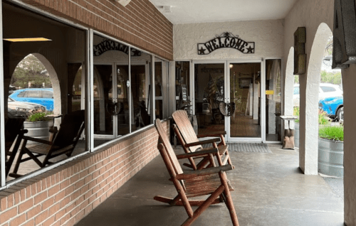 A welcoming entrance with rocking chairs and large windows reflecting the surroundings.